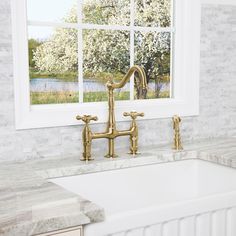 a kitchen sink with two faucets in front of a window