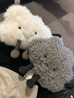 two stuffed animals sitting next to each other on top of a blanket and chair cushion