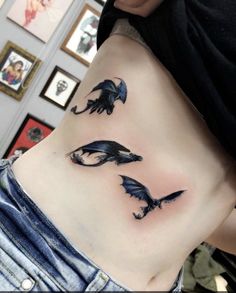 a woman's stomach with three black dragon tattoos on her side and the bottom