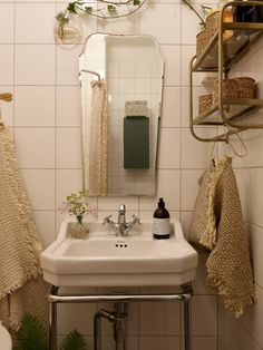 a white sink sitting under a bathroom mirror next to a shelf with towels on it