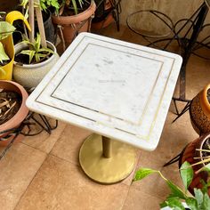 a marble top table surrounded by potted plants and other pots on the ground in front of it