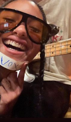 a man with glasses holding up a fake guitar string to his face and smiling at the camera