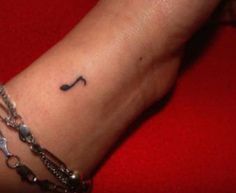 a woman's arm with a music note tattoo on the left side of her wrist