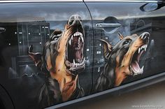 two dogs with their mouths open are painted on the side of a black car,