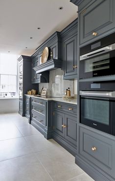 a kitchen with gray cabinets and marble counter tops