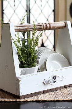 a wooden tray with dishes and plants in it