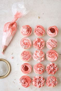 cupcakes with pink frosting and sprinkles on a table