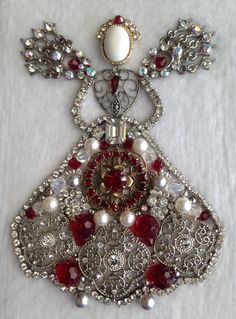 an elaborate necklace with red and white beads, pearls, and other jewels on it