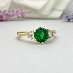 a close up of a ring with a green stone in the middle and three diamonds around it