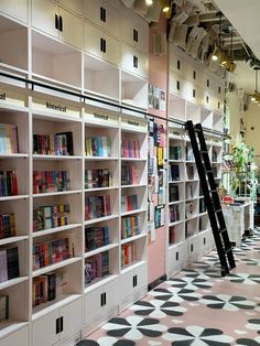 there is a ladder leaning up against the bookshelves in this library that are lined with white bookcases