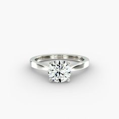 a white gold engagement ring with a round brilliant cut diamond in the center, on a plain surface