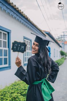 a woman in graduation gown holding up a sign that says i'm for him