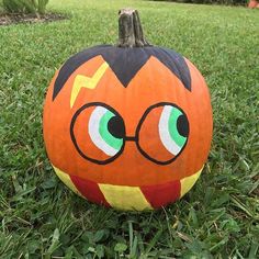 a pumpkin with glasses painted on it sitting in the grass