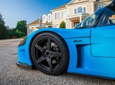 a blue sports car parked in front of a large house