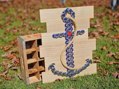 an anchor made out of glass beads sits in the grass next to a wooden crate