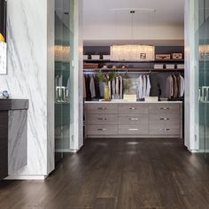 a walk in closet with wooden flooring and glass doors that lead to the bedroom