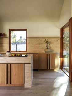 a kitchen with wooden cabinets and an island in the middle is seen from across the room