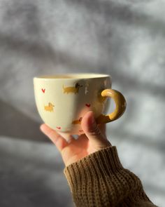 a hand holding a coffee cup in front of a white background with dogs on it