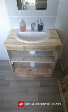 a white sink sitting under a bathroom mirror next to a wooden shelf with soap and toothbrushes on it