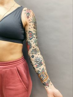 a woman with tattoos on her arm and arms is standing in front of a wall