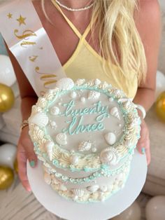 a woman holding a cake with the words twenty nine on it and pearls around her neck