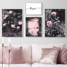 three pink roses are hanging on the wall next to a white couch and two candles