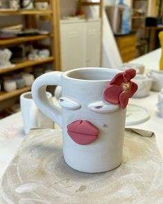 a coffee cup with a face painted on the side and a flower sticking out of it