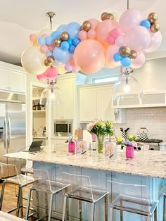 the balloons are hanging from the ceiling above the kitchen island and bar stools in front of it