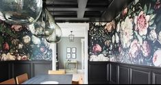 a dining room with floral wallpaper and wooden table in front of black paneled walls