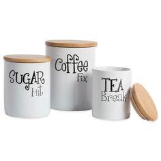 three white coffee canisters with wooden lids, one has a tea in it