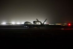 an airplane on the runway at night with lights in the dark behind it and foggy skies