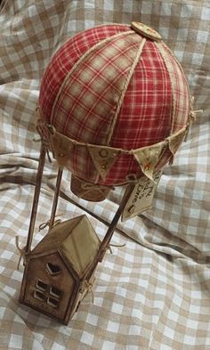 a small red and white balloon with a house on it's side sitting on a bed