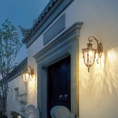 two white chairs sitting in front of a door with lights on it's side