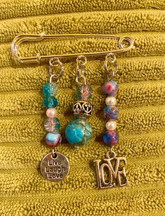 three charms hanging from a towel on top of a yellow blanket with the word love