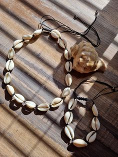 These stunning Cowrie shell Necklace and bracelet sets are any shell or beach lovers dream!  Available in 2 colours: White cord  and Black cord. Measurements shown in pics. Cowrie shells are associated with prosperity, wealth and protection. They symbolise a connection with the ocean and ancestral spirits and are often used in various cultural and spiritual practices. Cowrie shells are also known as symbols of womanhood, fertility, birth and wealth. They have the energy of an ocean goddess, brin Adjustable Shell Jewelry In Beachy Style, Beach Season Cowrie Shell Jewelry, Adjustable Beachy Shell Jewelry, Adjustable Shell Beachy Jewelry, Adjustable Cowrie Shell Jewelry For Beach Season, Adjustable Cowrie Shell Beachy Jewelry, Adjustable Strand Shell Necklace For Beach, Adjustable Shell Jewelry For The Beach, Adjustable Beachy Cowrie Shell