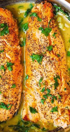 two fish fillets in a skillet with herbs on top, ready to be cooked