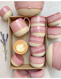 a box filled with pink and white pottery next to some lavender sprigs on the table