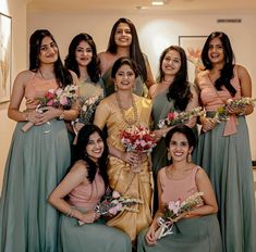 a group of women standing next to each other holding bouquets in their hands and smiling at the camera