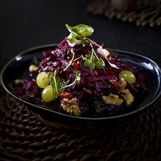 a plate that has some kind of food on it with grapes and nuts in it