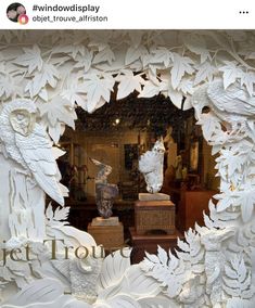 an image of a window display with white paper flowers and angel statues in it's center