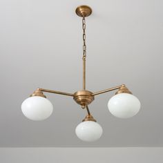 three light brass chandelier with white glass globes hanging from it's ceiling