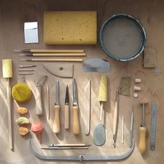 various tools are laid out on a wooden surface with some paintbrushes and other items