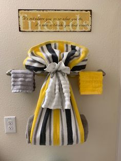 two towels are hanging on the wall next to a towel rack with yellow and black striped towels