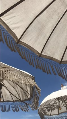 two umbrellas with fringed edges against a blue sky