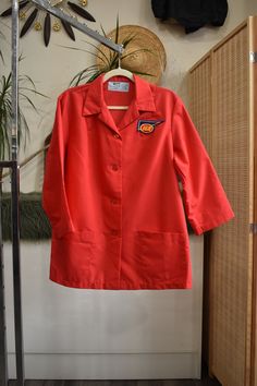 1970s retro cherry red IGA supermarket uniform work shirt // workwear jacket with wide sleeves, retro butterfly collar, and patch pockets. Looks like something a gas station attendant, butcher, or mechanic would wear. Loose tented fit. By Angelica. Wash and wear! Technically womens but fits like a unisex large Shoulders 18" Chest 48" Sleeve 19" Arm Hole 11" Length 29.5" Orange Workwear Top With Pockets, Retro Outerwear For Office, Retro Cotton Outerwear For Work, Retro Red Tops With Pockets, Vintage Orange Outerwear For Workwear, Vintage Outerwear With Pockets And Short Sleeves, Red Tops With Pockets For Workwear, Red Workwear Top With Pockets, Store Uniform