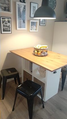 a kitchen table with two stools underneath it and pictures on the wall behind it