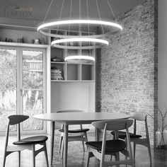 a black and white photo of a dining room table with four chairs around it in front of a brick wall