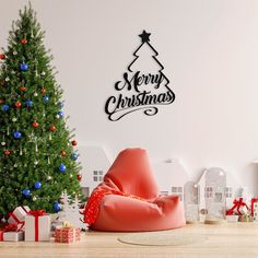 a christmas tree and presents in front of a wall decal that says merry christmas