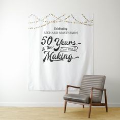 a chair sitting in front of a white wall with a banner hanging above it that says 50 years of the making