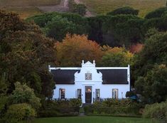 a white house surrounded by trees and bushes